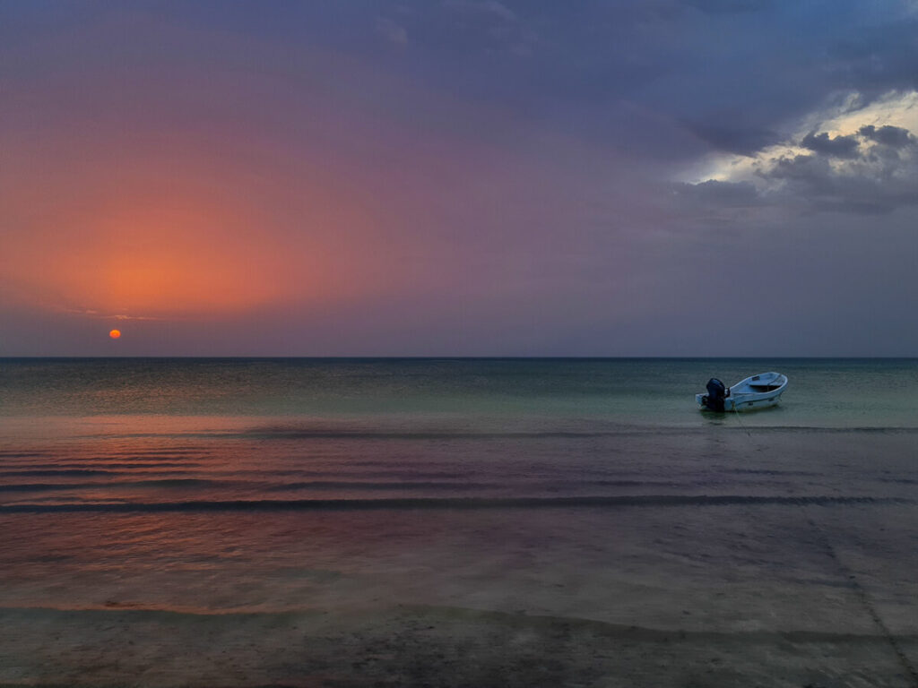 An orange and pruple sunset reflecting on the calm sea off Playa Holbox.