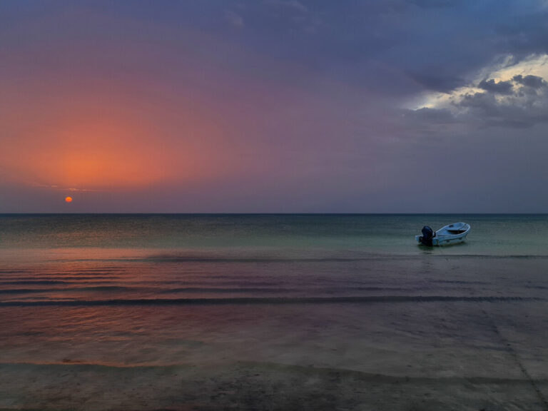 An orange and pruple sunset reflecting on the calm sea off Playa Holbox.
