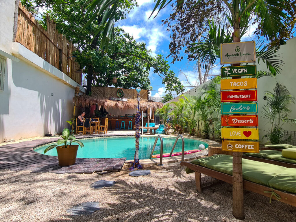 A pool and colourful sign in a courtyard in a hotel in Tulum, Mexico.