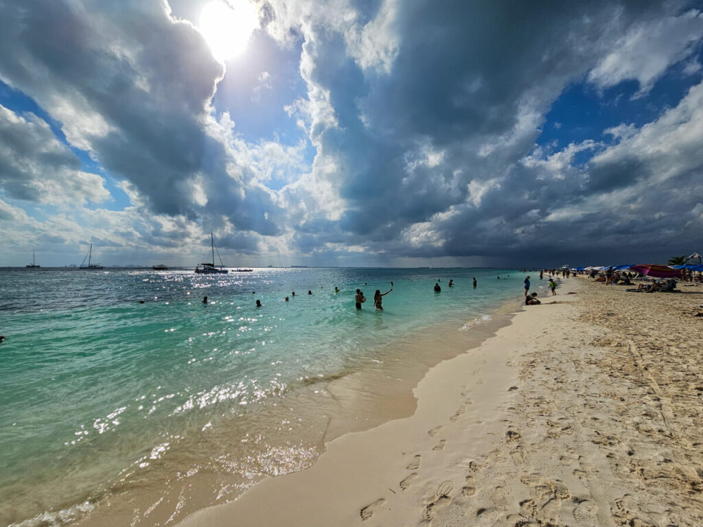 People wading in the turquoise waters on a beach on Isla Mujeres.