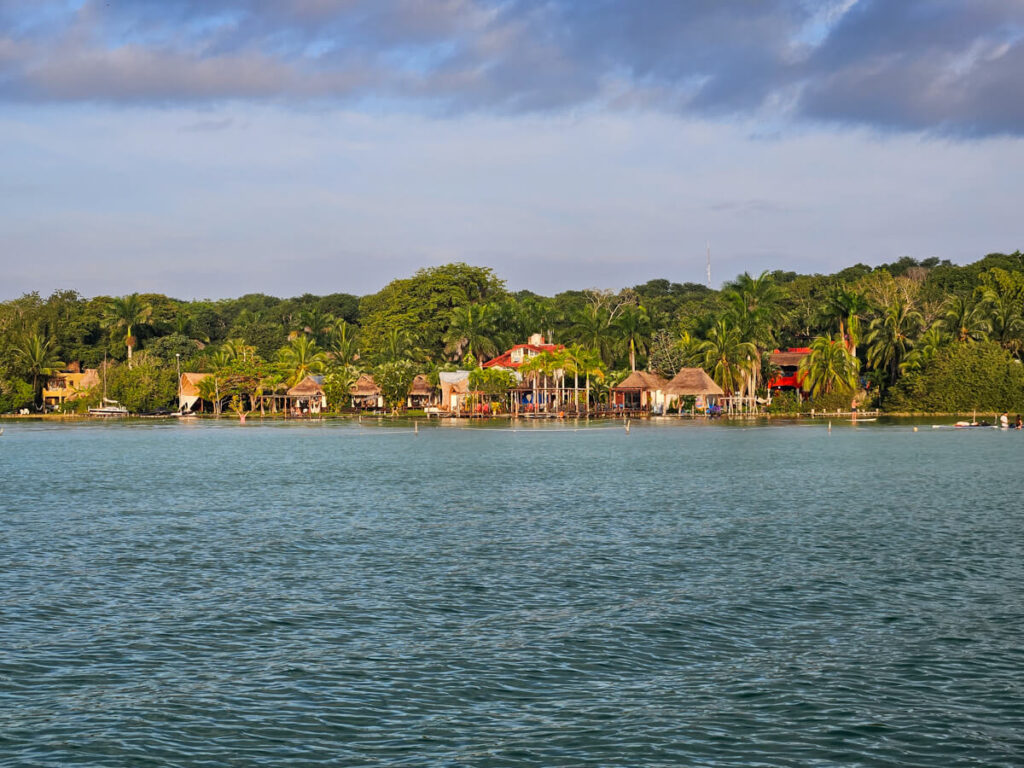 Hotels on the water of Bacalar Lagoon. Golden early morning light is illuminating the buildings and their docks.