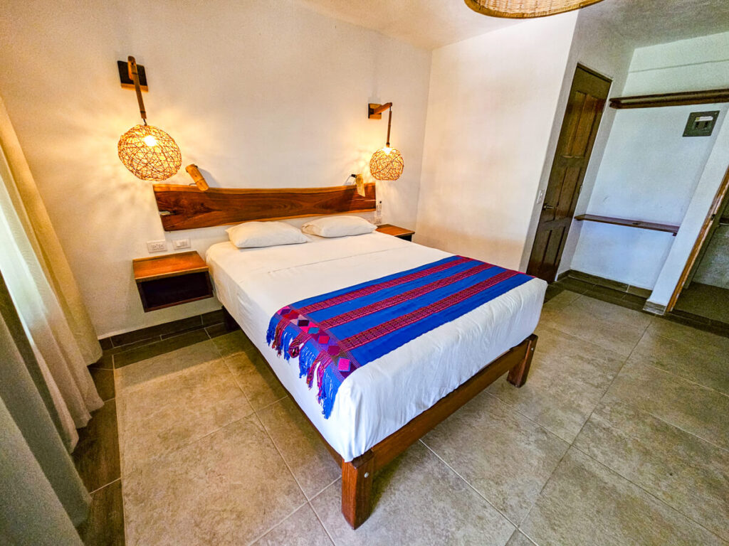 A double bed with chic light fittings and mahogany bedside tables. This is an example of one of the bedrooms at Casa Lamat.