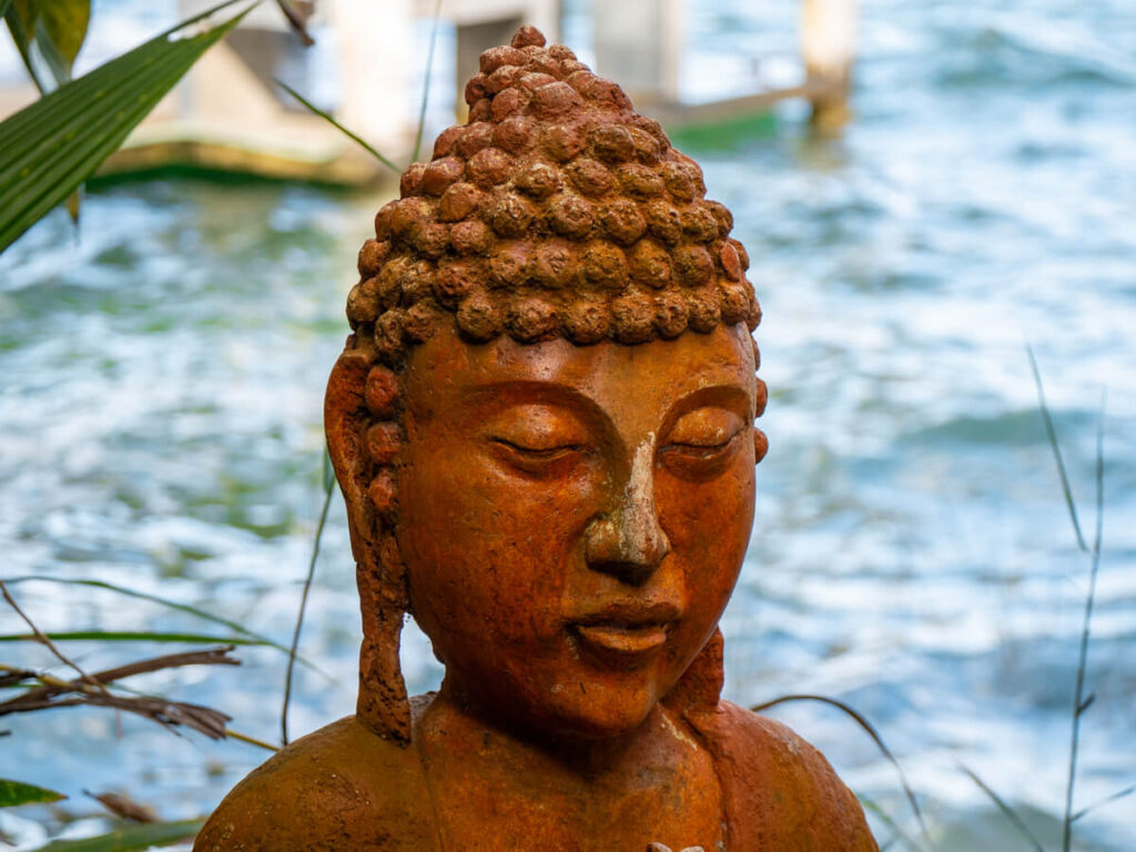 The head of a hand-carved Buddha sculpture. The clay is slightly weather-worn around the nose.