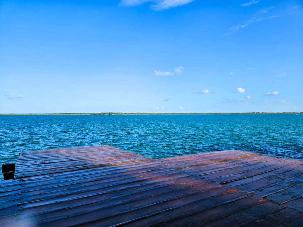 Bacalar lagoon as viewed from an empty wooden dock in the sunshine.