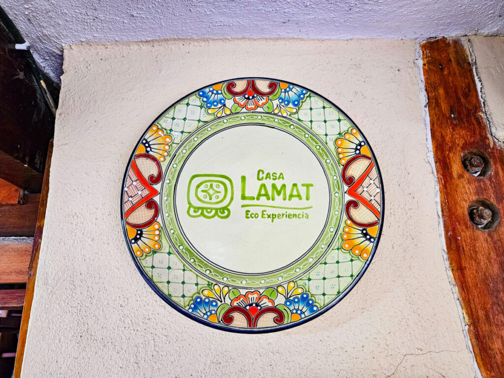 A circular painting on a wall with flower patterns around the outside and the words "Casa Lamat Eco Experiencia".