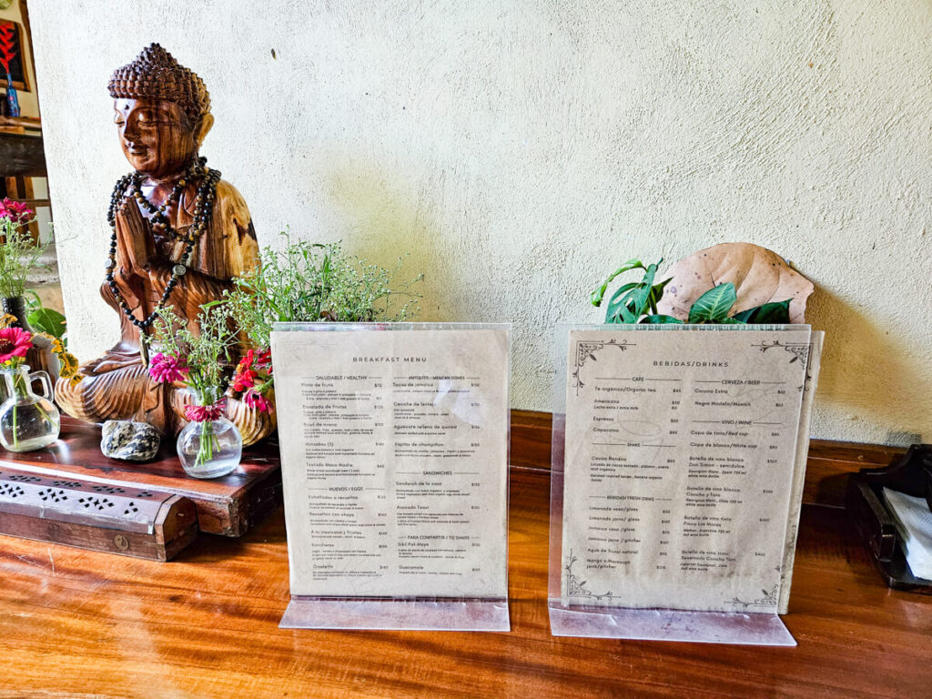 The food and drinks menus displaying what is on offer at the Casa Lamat restaurant. These menus have been placed next to a small sculpture of Budda.