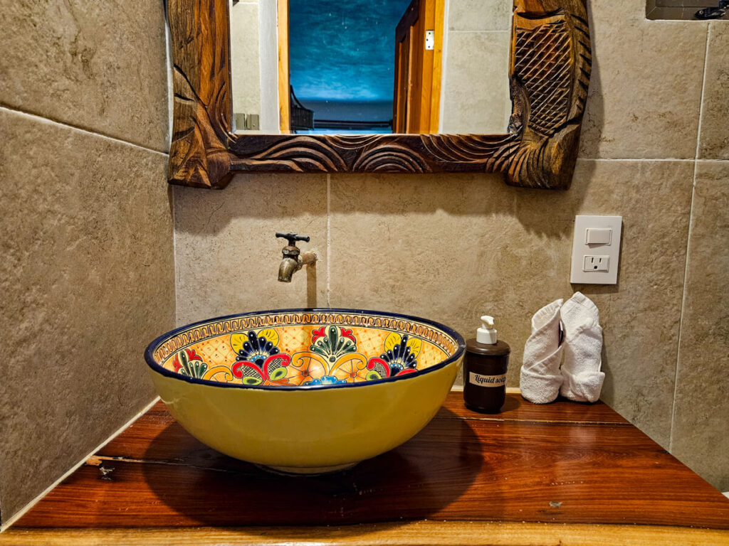 A hand-painted wash basin on a mahogany countertop in a bathroom at Casa Lamat.