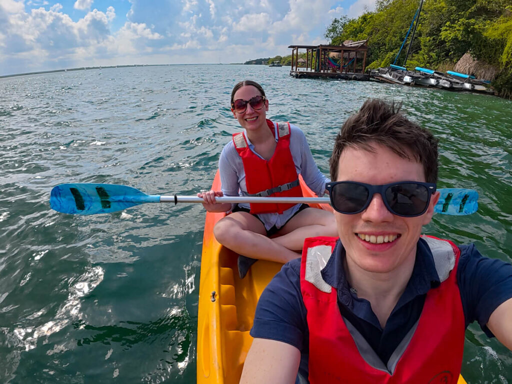 Dan and Lucy smiling as they sit in a two-person kayak on Bacalar Lagoon.
