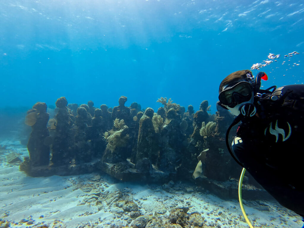 Dan SCUBA diving with countless submerged sculptures at the MUSA Underwater Museum near Isla Mujeres.