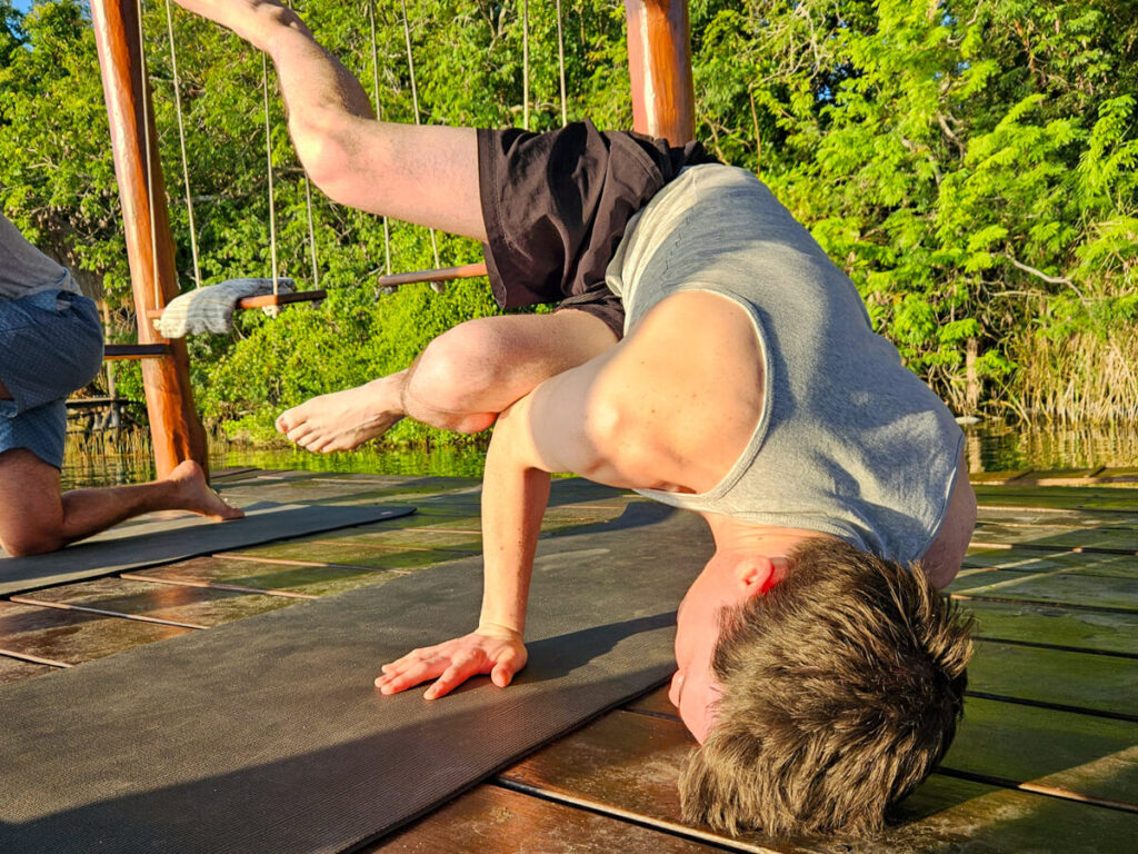 Dan at a yoga class holding himself up on his hands in a 'side-crow' pose.