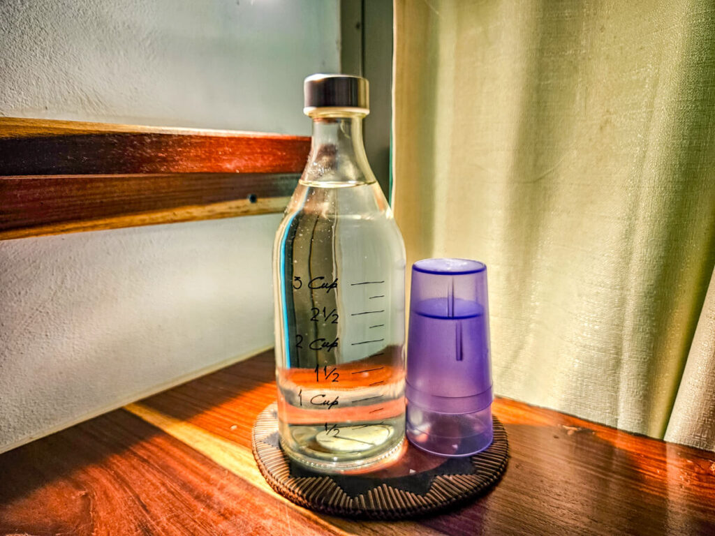 A glass bottle of water and some drinking cups. Fresh water is provided at Eco-hotel Casa Lamat to all guests.