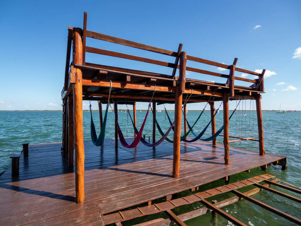 The wooden docks at Eco Hotel Casa Lamat. Several hammocks are hanging in the dock and the sun is shining brightly.