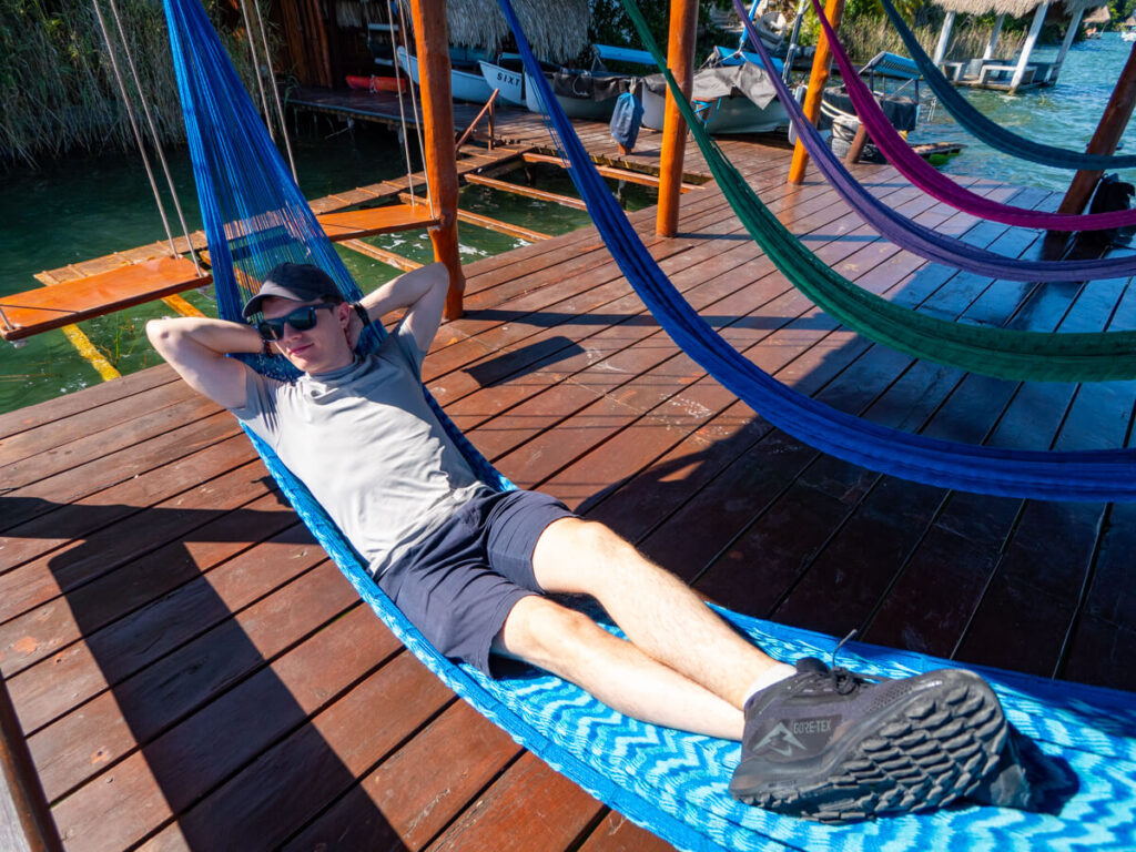 Dan relaxing on a hammock at the Eco Hotel Casa Lamat. There is a line of empty hammocks beside him, each one a different colour.
