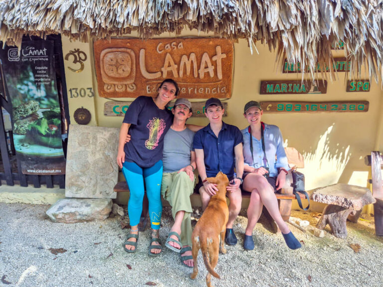 Dan and Lucy sitting beside Xavy and Xere at the Eco Hotel Casa Lamat, Bacalar. They are sitting in front of the entrance to Casa Lamat and are joined by a friendly dog that Dan is petting.