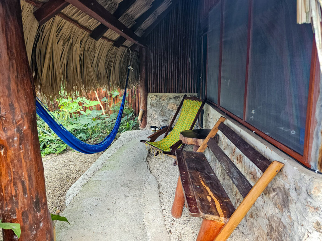 Outside seating at Casa Lamat including a bench, a deck chair, and a hammock.