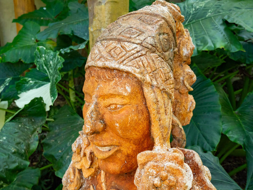 The head of a hand-carved sculpture depicting a Peruvian man in a patterned hat.
