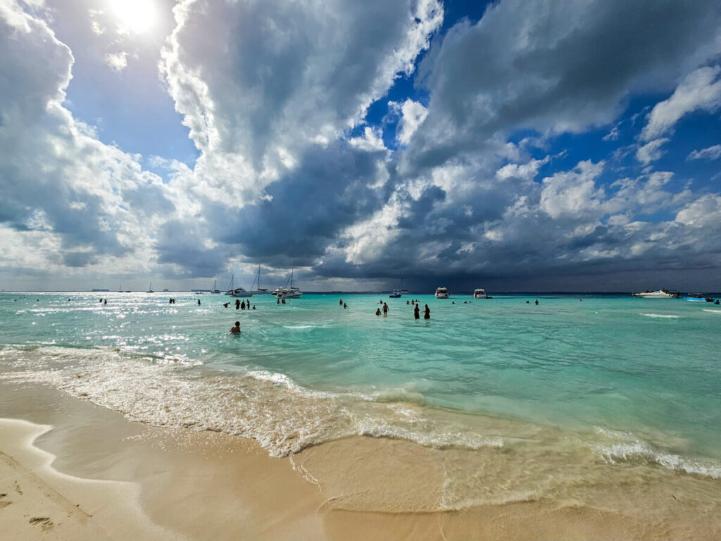 One of the best beaches in the world, Playa Norte on Isla Mujeres. The sky is moody and the sea is a milky blue colour.
