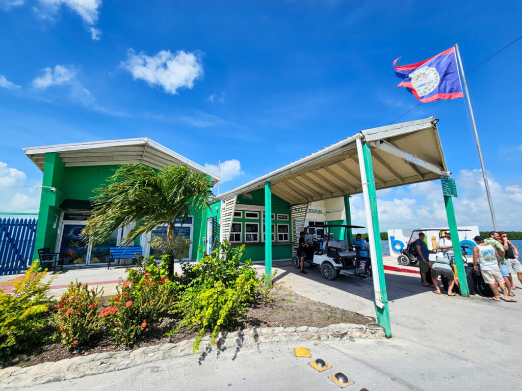 Outside San Pedro Ferry Terminal on a sunny day. Tourists are waiting for taxis and golf cart rentals.