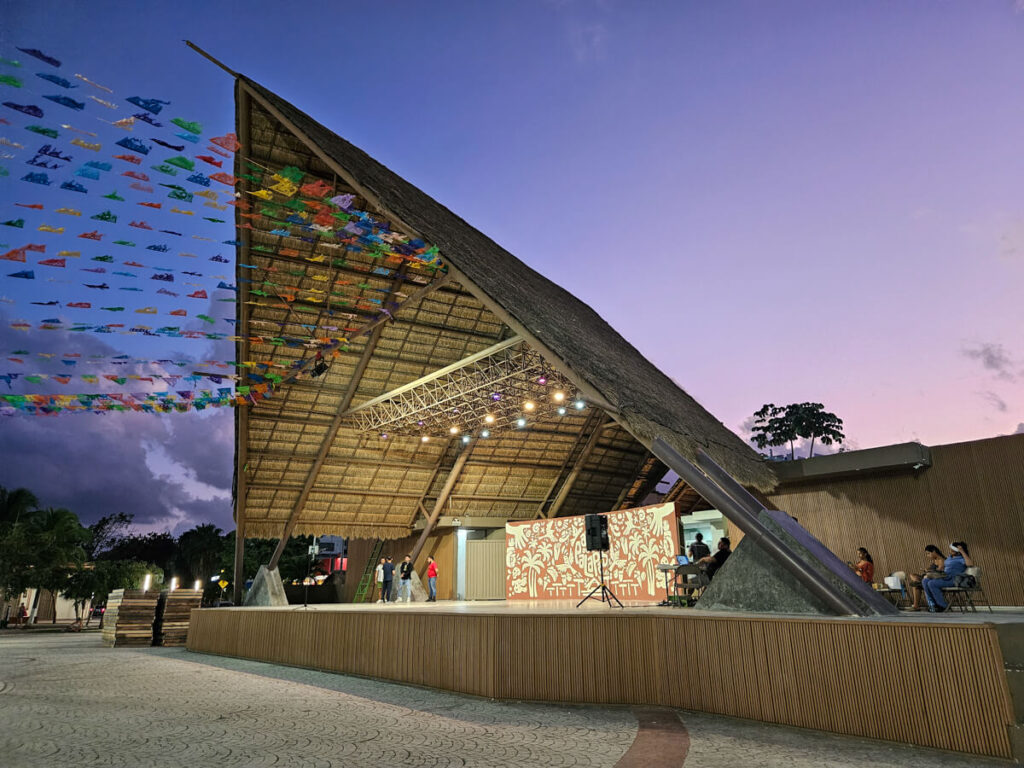 A purple sunset behind a large stage with a triangular roof in the outdoor food market, Parque de las Palapas in Cancún.