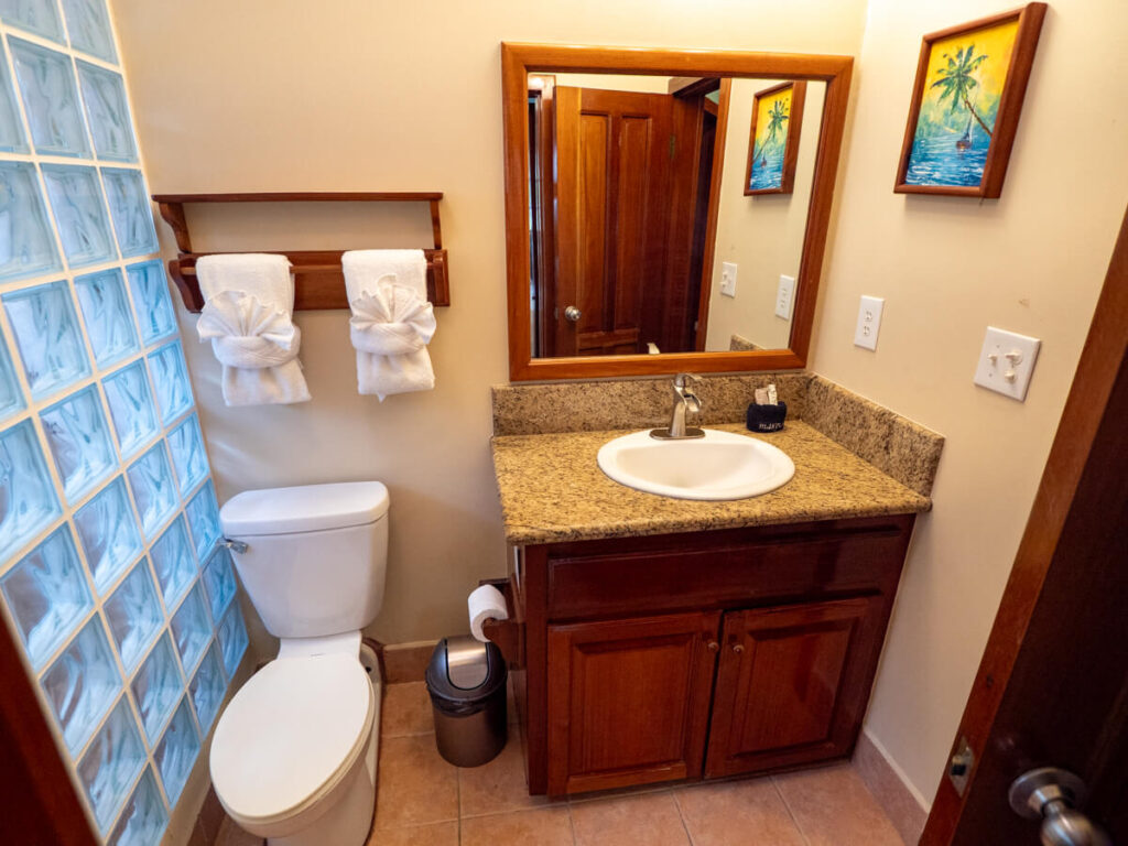A bathroom at Belizean Shores Resort. The walls are white and the floor tiles are flush and clean.