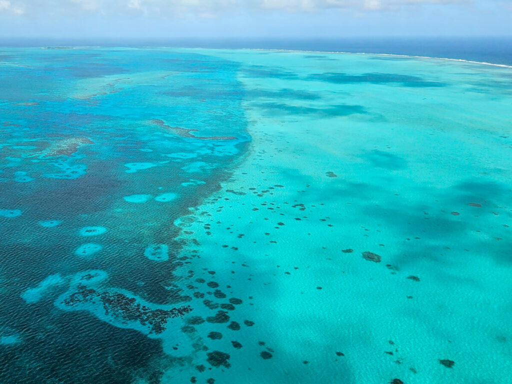 A colourful Belizean atoll viewed from a low-flying plane above the water.