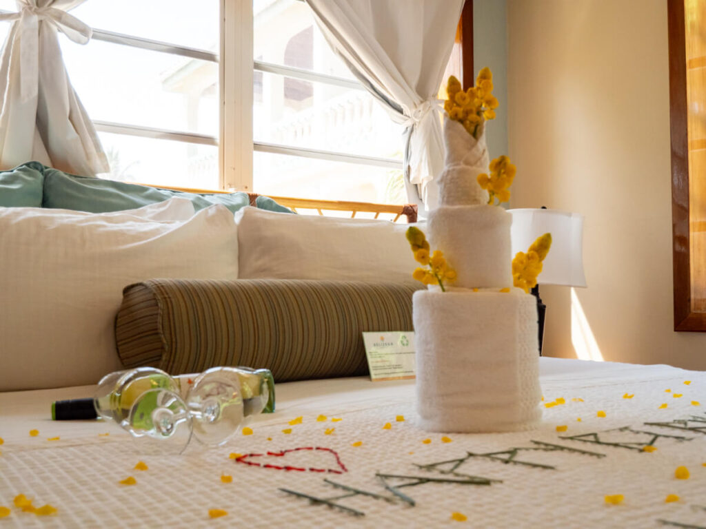Towels on a bed arranged to look like a multi-level birthday cake decorated with fresh flowers.