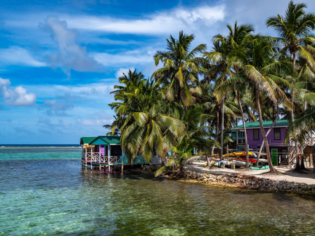 Colourful overwater bungalows on stilts on the shore of Tobacco Caye, Belize.