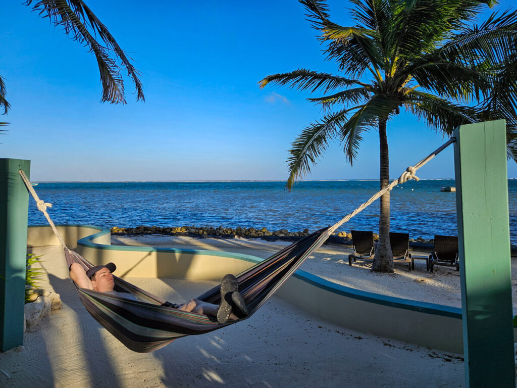 Dan relaxing with his eyes closed on an outside hammock by the sea at Belizean Shores Resort.