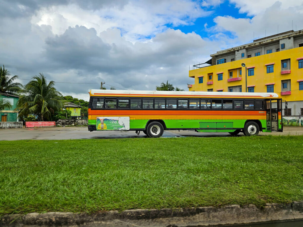 A green and orange local bus in Dangriga, Belize.