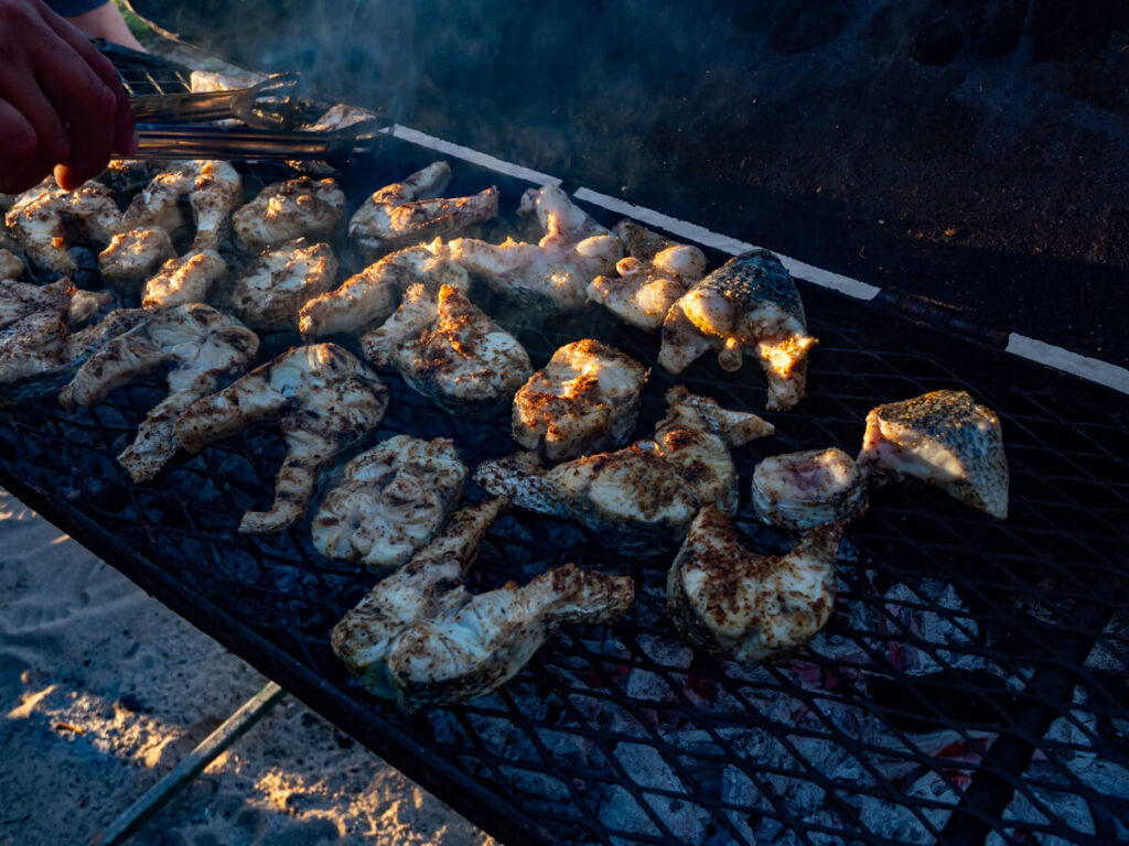 A selection of fresh fish pieces cooking on an open BBQ.