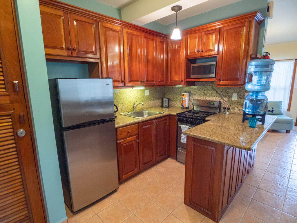 A fully-equipped kitchen in one of the suites at Belizean Shores Resort. There is a fresh water dispenser, microwave, fridge-freezer, cooker, and toaster.