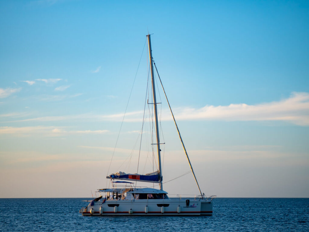 The Ragga Pheonix sailboat in the afternoon light, against a clear horizon.