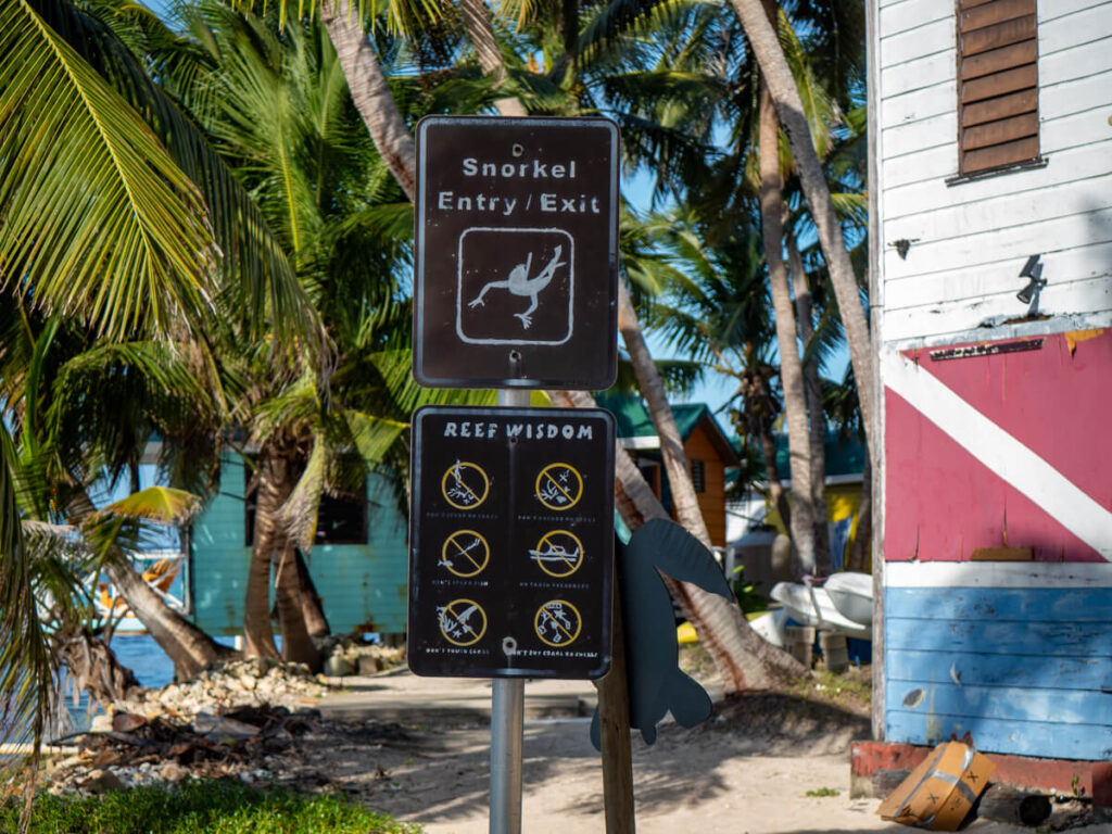 A snorkel entry and exit sign on Tobacco Caye. Underneath is a series of pictures depicting rules in place to protect the reef.