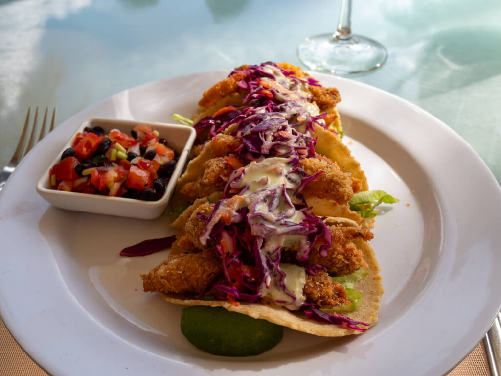 A plate of Baja-style fish tacos on a table outside in the sunshine.