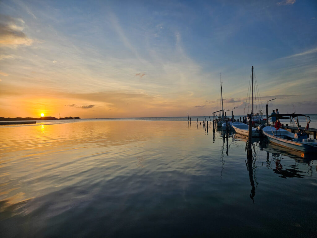 A stunning view of the sunset from the the Pelican Sunset Bar in Caye Caulker. The still waters of the coast are reflecting the amber colours of the sky.