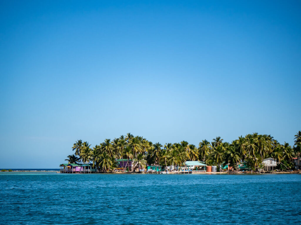 The palm trees and bungalows of Tobacco Caye as viewed from a sailboat on an overnight sailing trip in Belize.