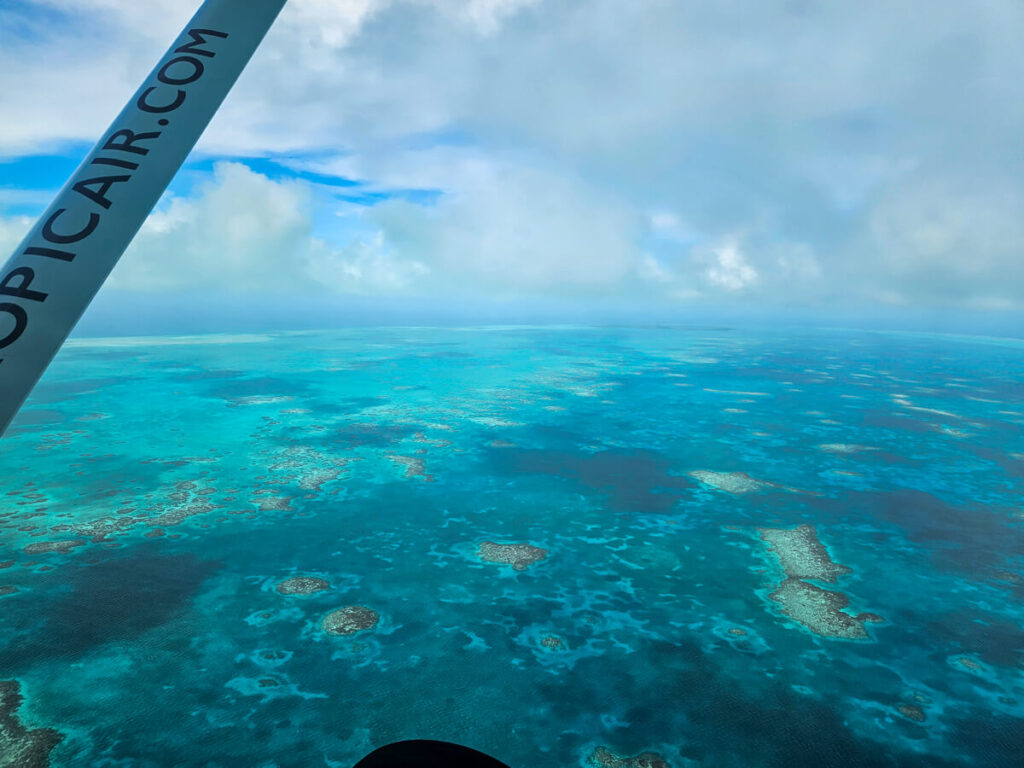 The view out of a plane window of islands and coral formations around the Belize Barrier Reef.