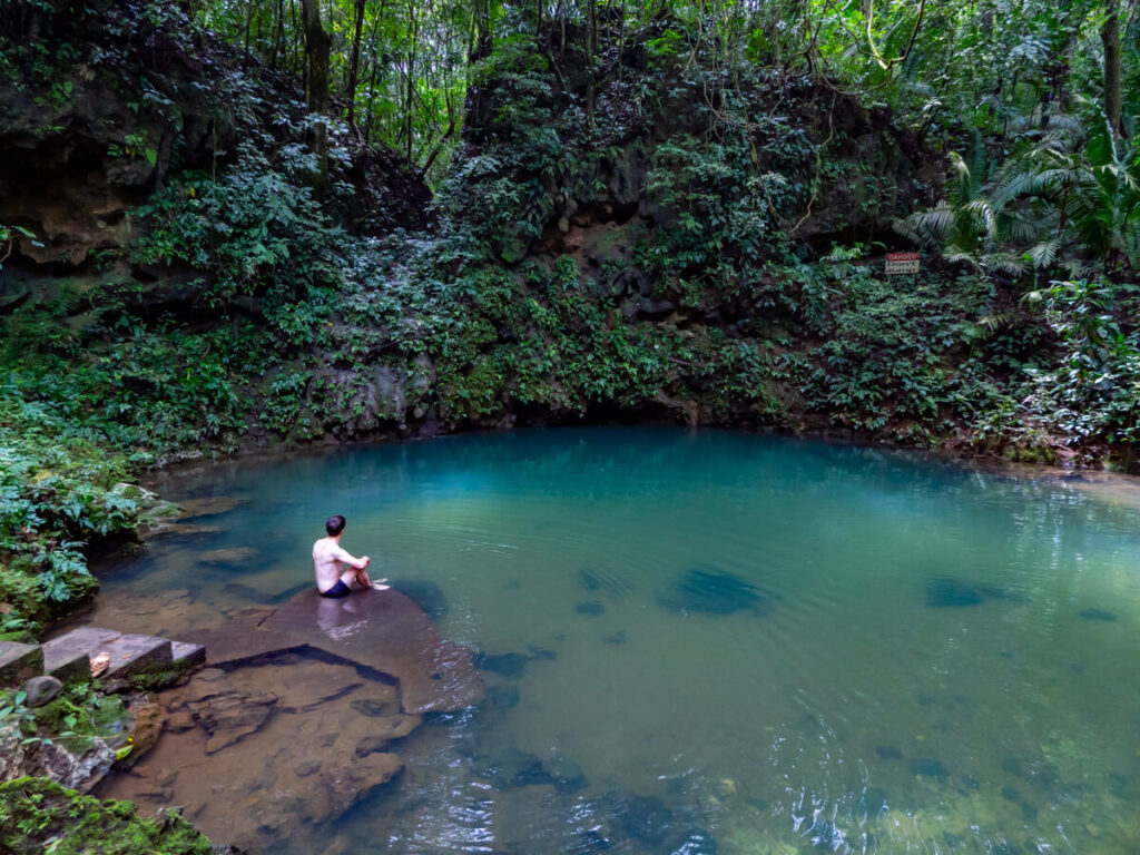 Dan sitting at the edge of the turquoise inland Blue Hole in St. Herman's Blue Hole National Park.
