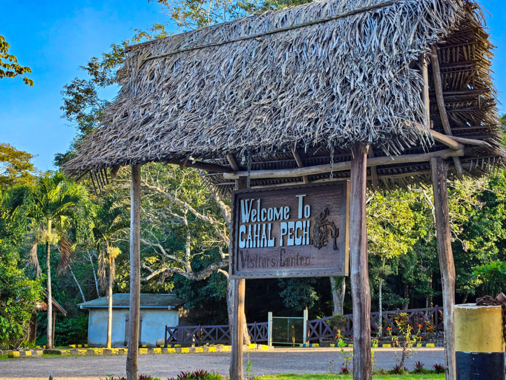 A traditional palapa style roof covering the sign which marks the entrance to the Cahal Pech Visitors' Center.