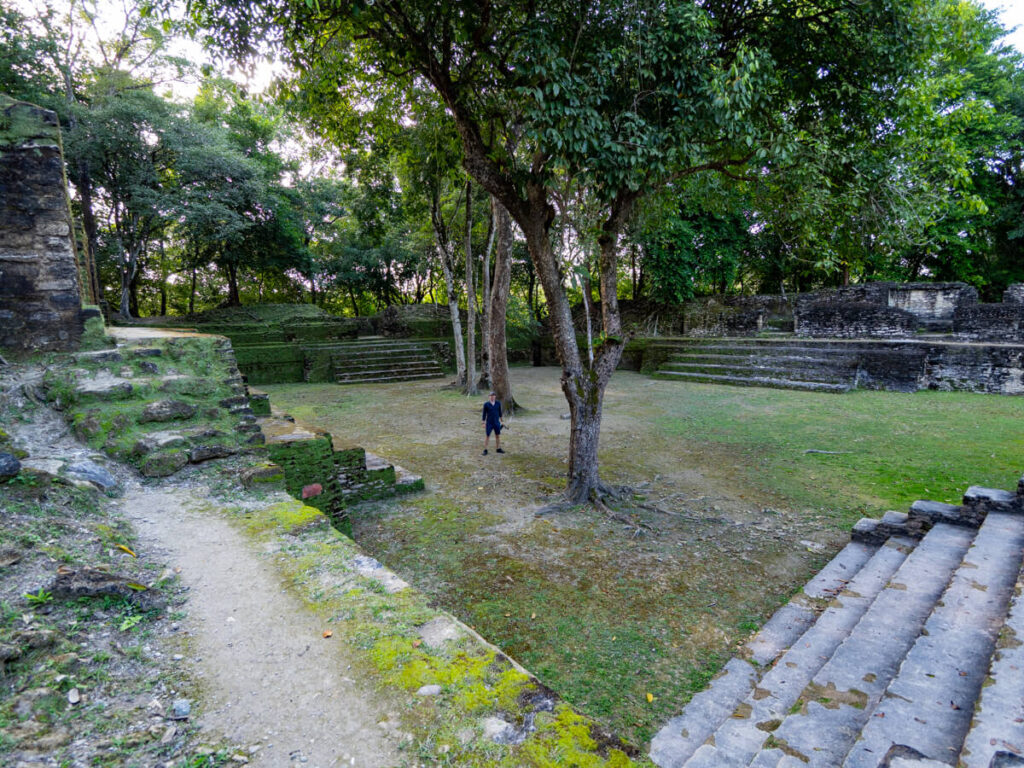 Dan standing in a large grassy courtyard in a Mayan archaeological site in Belize.