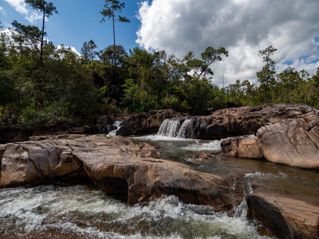 A serene waterfall cascading in the river at Rio On Pools natural swimming hole in the Mountain Pine Ridge Forest Reserve.