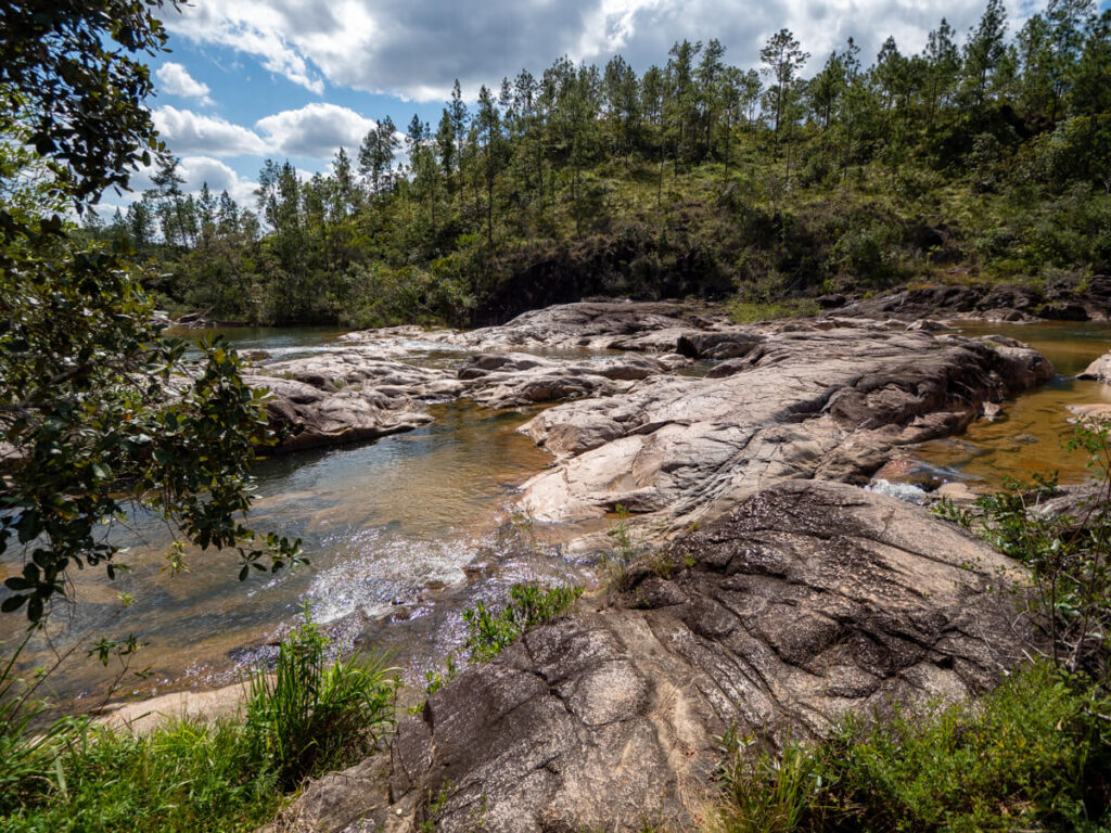 A serene river winding through a valley in the Mountain Pine Ridge Forest Reserve.
