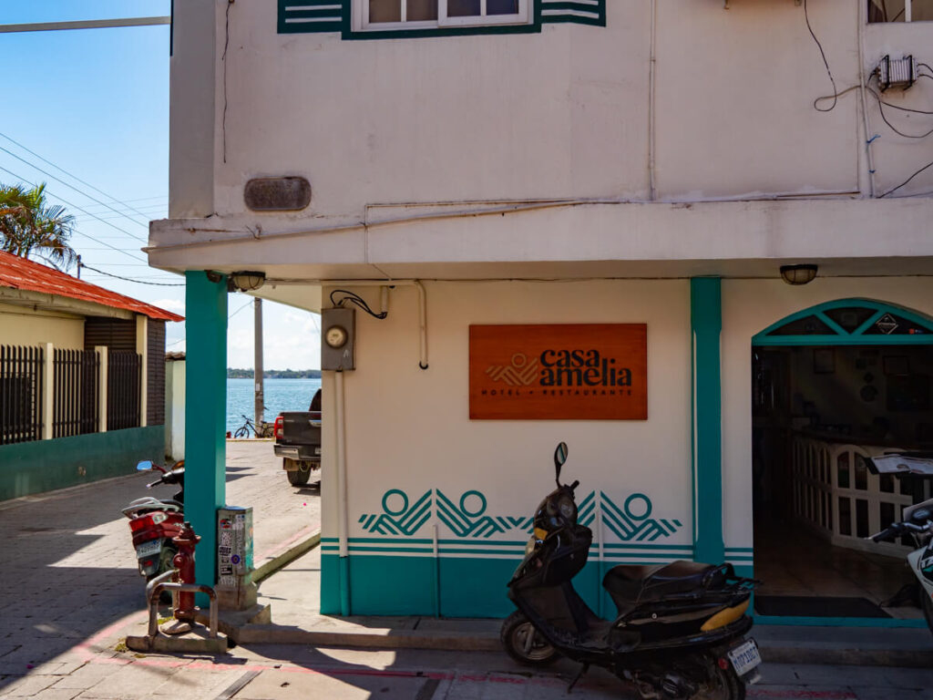 A scooter parked outside the white and turquoise decorated walls of Hotel Casa, Amelia, one of the best places to stay in Flores, Guatemala.