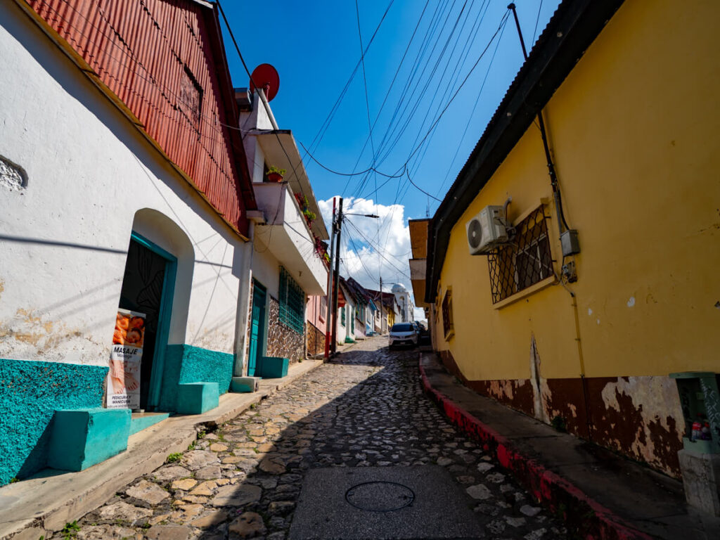 A sloped cobbled street lined by colourful buildings on Isla de Flores, Guatemala.