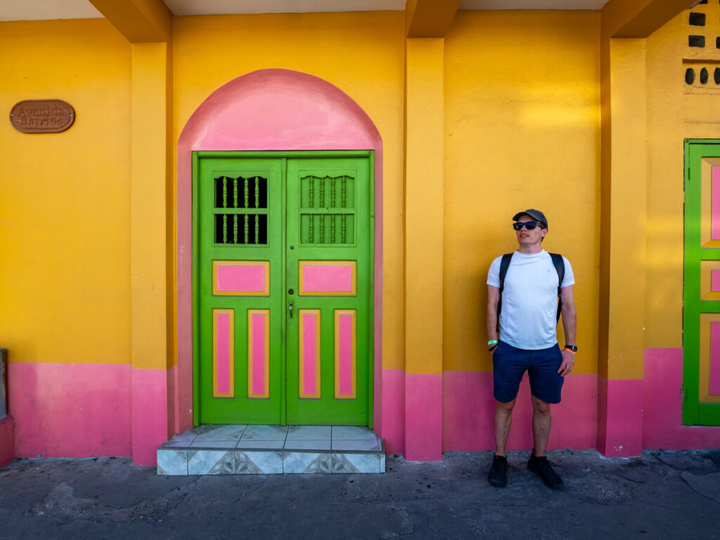 Dan standing in front of a yellow and pink building with a green door in Isla de Flores, Guatemala.