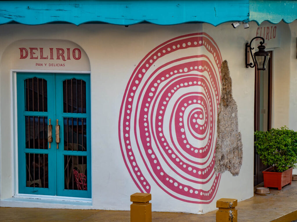 A pink patterned spiral painted on the white wall of Delirio bakery in Flores, Guatemala.