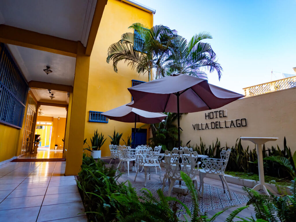 An open courtyard with seating, umbrellas, and plants in Hotel Villa del Lago, one of the best hotels in Isla de Flores, Gutemala.