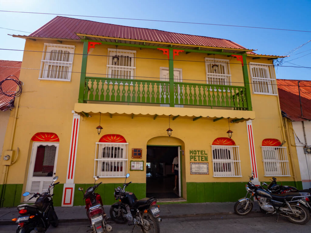 The yellow façade of Hotel Peten with green balconies in Isla de Flores, Guatemala.