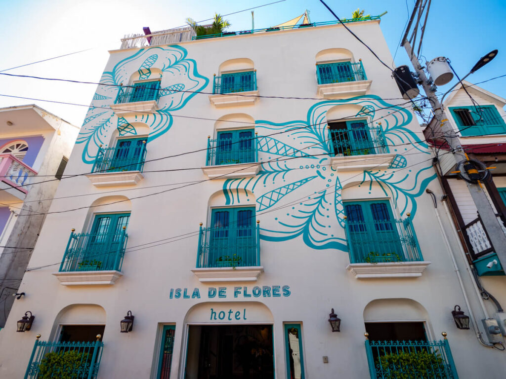 The beautiful façade of Hotel Isla de Flores painted white with turquoise flowers, one of the best boutique hotels in Flores, Guatemala.