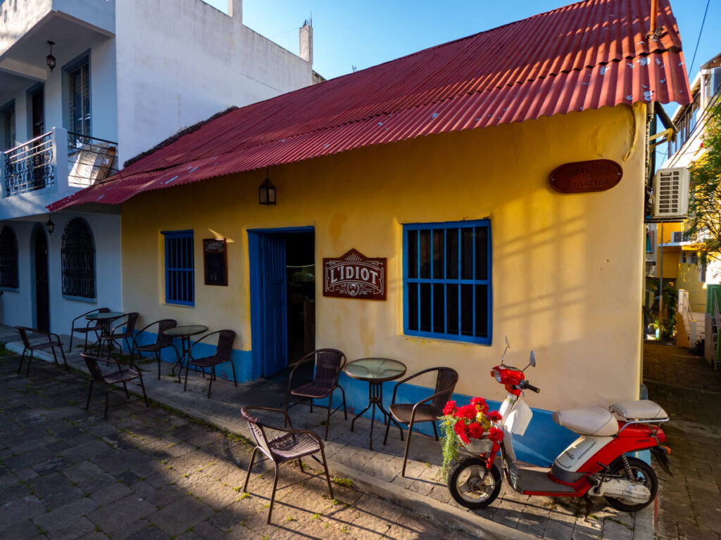 Seats outside the yellow exterior of L'idiot Bar in Flores, Guatemala.
